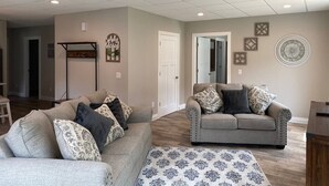 A spacious living room with two sofas, a patterned rug, and a ceiling with recessed lighting.