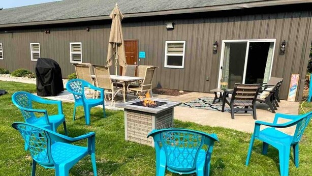 A patio area with outdoor furniture, a fire pit, and a building in the background.