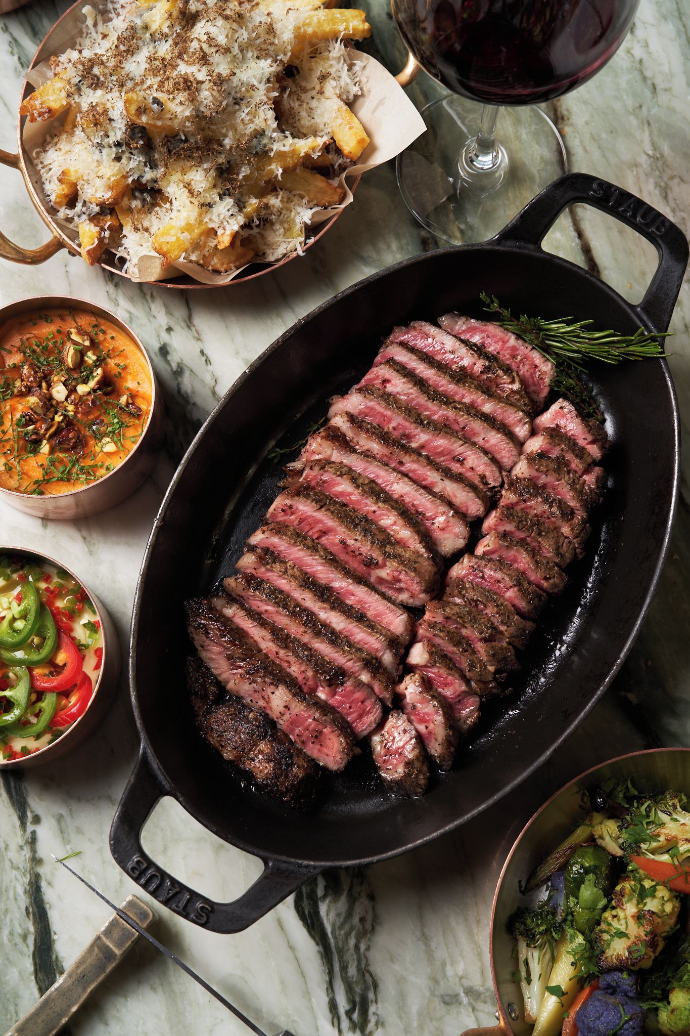 Un steak cuit à la poêle, accompagné de légumes et de pain.