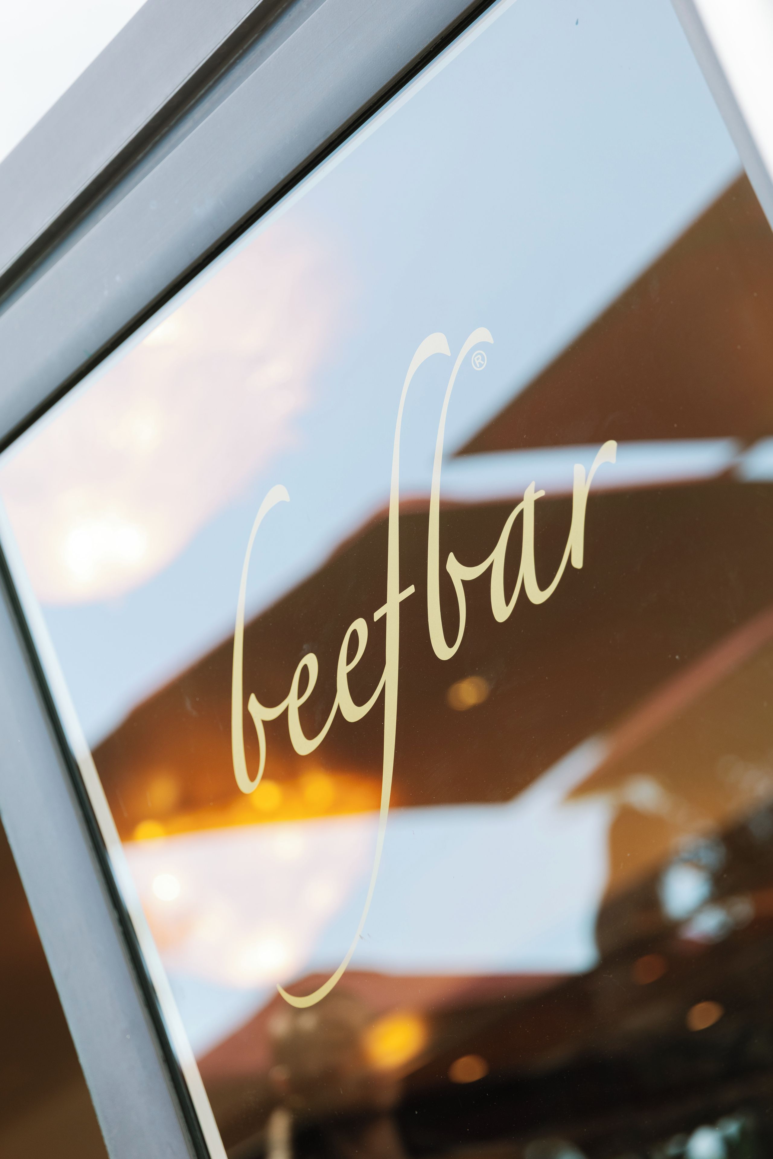 A framed sign with the word 'beefbar' in cursive script.