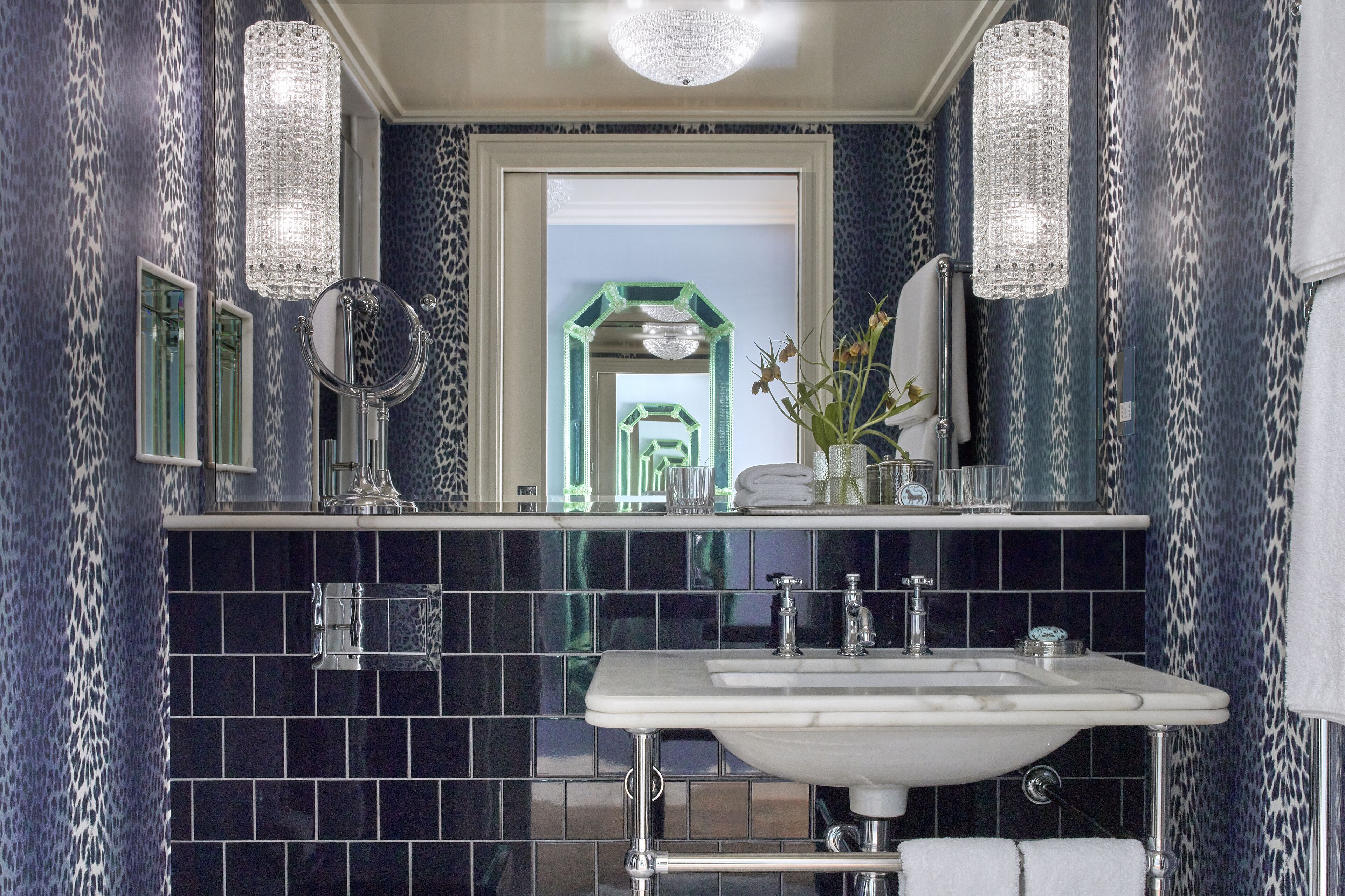 Une salle de bain avec un lavabo blanc, deux miroirs et un miroir encadré de vert.
