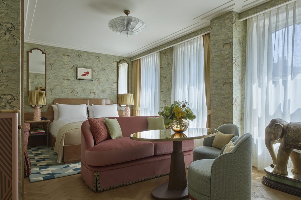 Una habitación de hotel con una cama, un sofá, una mesa redonda y una estatua decorativa de un elefante.