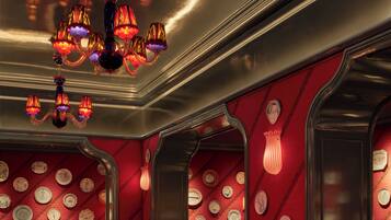 L’intérieur d’un restaurant avec des tables rondes, des chaises à revêtement rouge et un lustre.