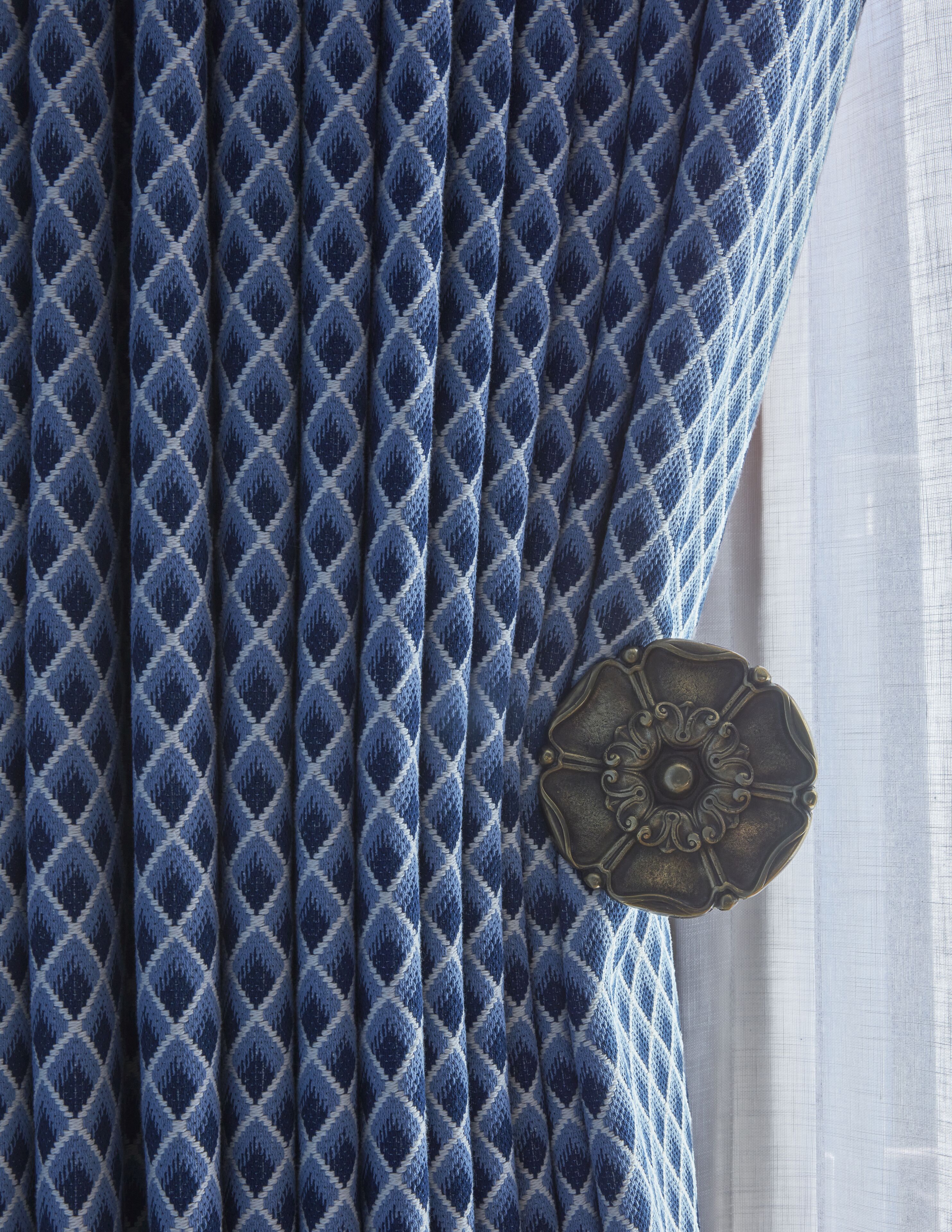 A close-up of a blue patterned fabric with a decorative metal button.