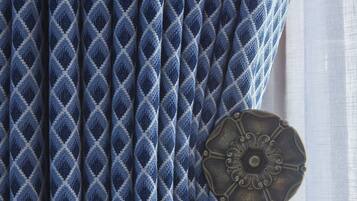 A close-up of a blue patterned fabric with a decorative metal button.