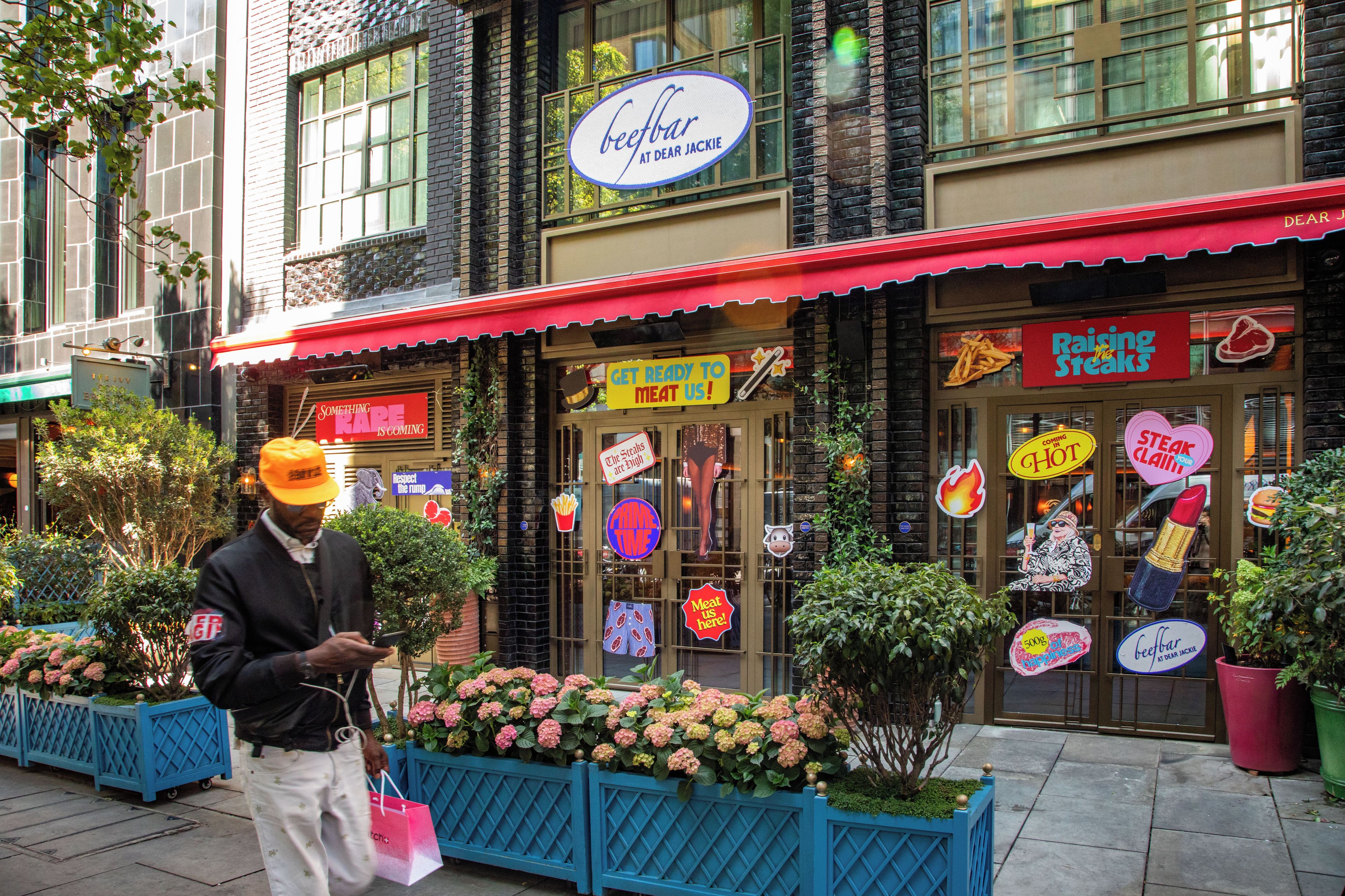 A storefront with a red awning and multiple colorful signs advertising meat products.