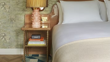 A hotel room with a bed, a nightstand with a lamp, a mirror, and a framed picture on the wall.