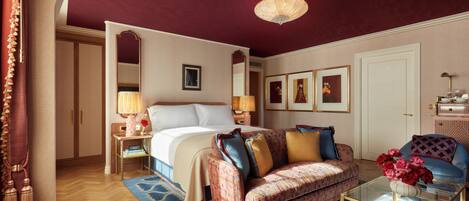 A well-furnished bedroom with a bed, a sofa, a glass coffee table, and a chandelier.