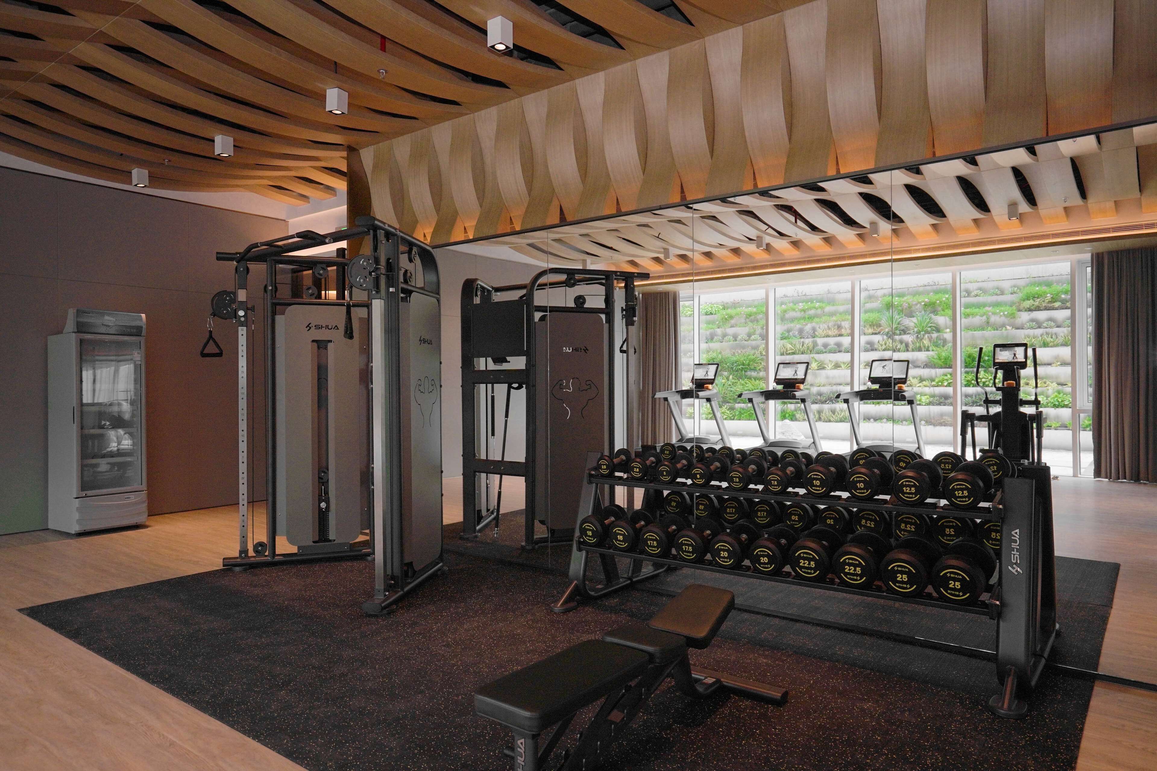 A gym with weightlifting equipment, dumbbells, and a bench.