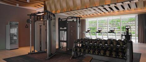 A gym with weightlifting equipment, dumbbells, and a bench.