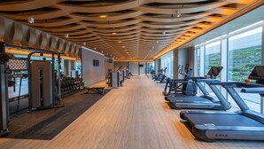 Une salle de sport équipée de tapis de course, d’appareils de musculation et dotée d’un plancher en bois.