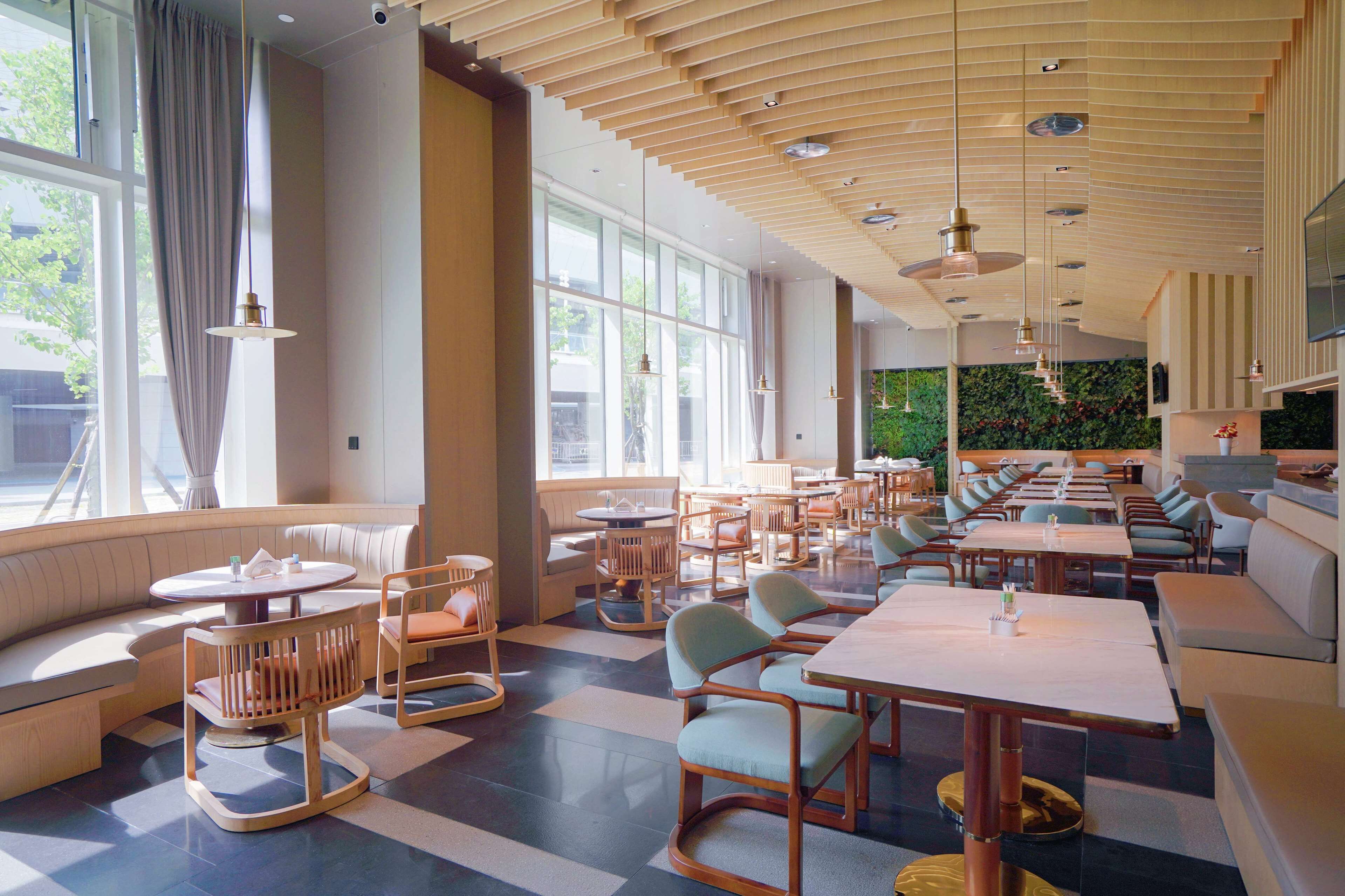 A spacious restaurant with high ceilings, large windows, and a variety of seating options including booths and tables.