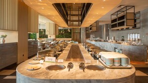 Un buffet composé de plusieurs points de service, d’un comptoir central où les plats sont présentés, et d’un espace repas avec des tables et des chaises.