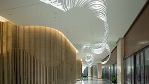 Un intérieur moderne avec un mur en bois aux lignes courbes et un luminaire au plafond au design original.