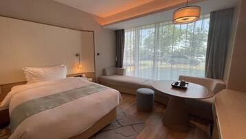 Habitación de hotel con cama, sofá, mesita y ventana con vistas al exterior.
