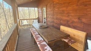 Terraza de madera con banco y mesa, rodeada de paredes y barandilla de madera.