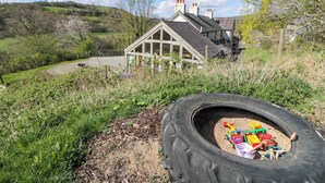 Ein Haus mit einem großen Sandkasten in Form eines Autoreifens im Vordergrund.