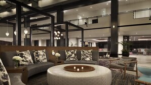 Een ruime lobby met een gebogen bank, een rond voetenbankje en een eethoek met tafels en stoelen.