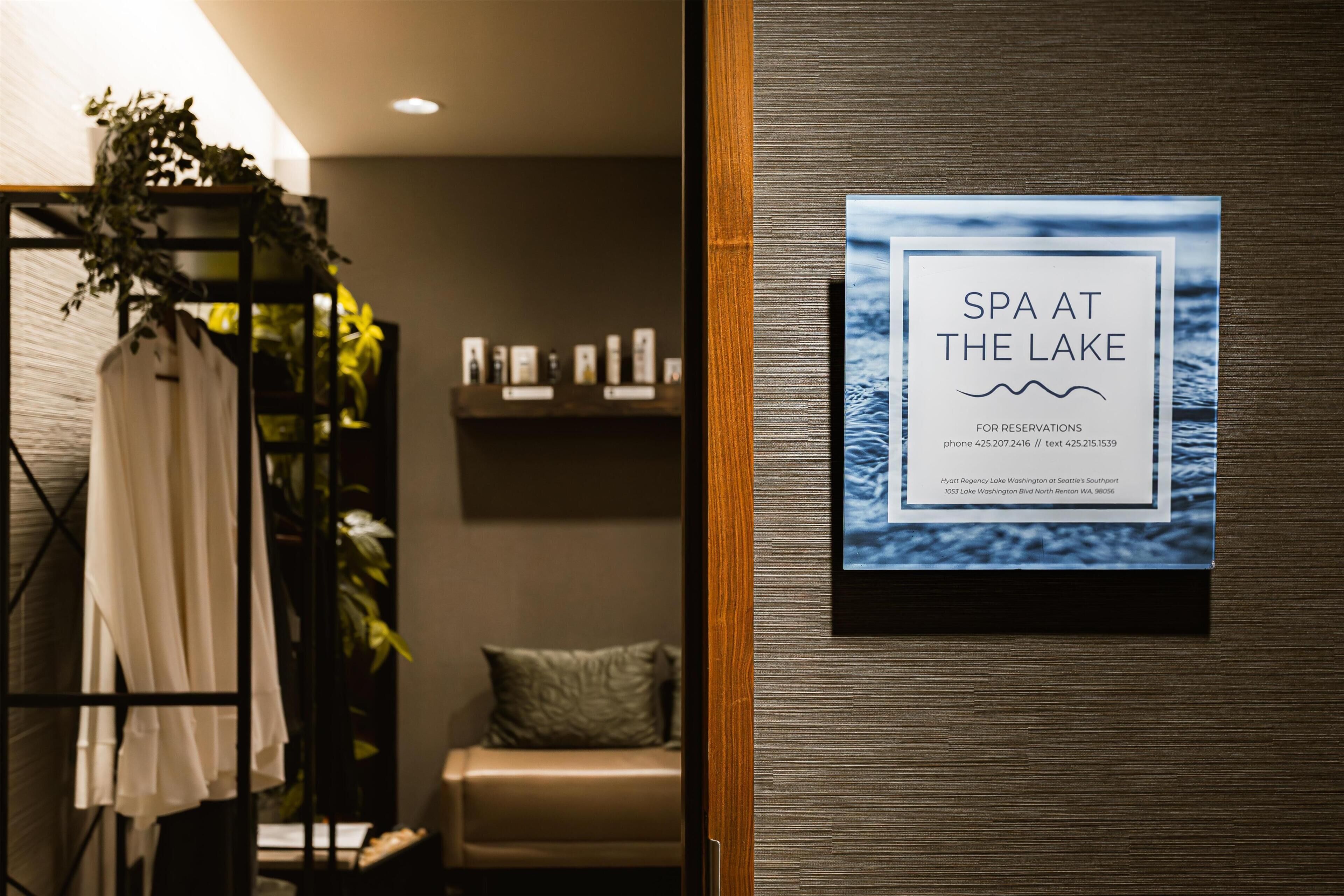 A spa sign with a lake view, a wooden shelf with items, and a plant.