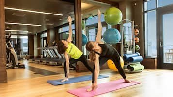 A gym with exercise equipment, yoga mats, and a large window.