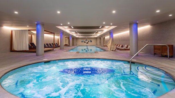 Un área de spa con hidromasaje, sillones de descanso y piscina.