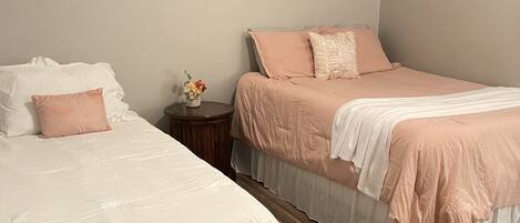 Un dormitorio con dos camas, una mesita de noche y un jarrón con flores.