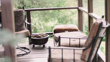 A wooden deck with two chairs and a small table, overlooking a green landscape.
