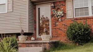 Une maison avec une façade en briques, une porte d’entrée et un petit porche doté de quelques marches.