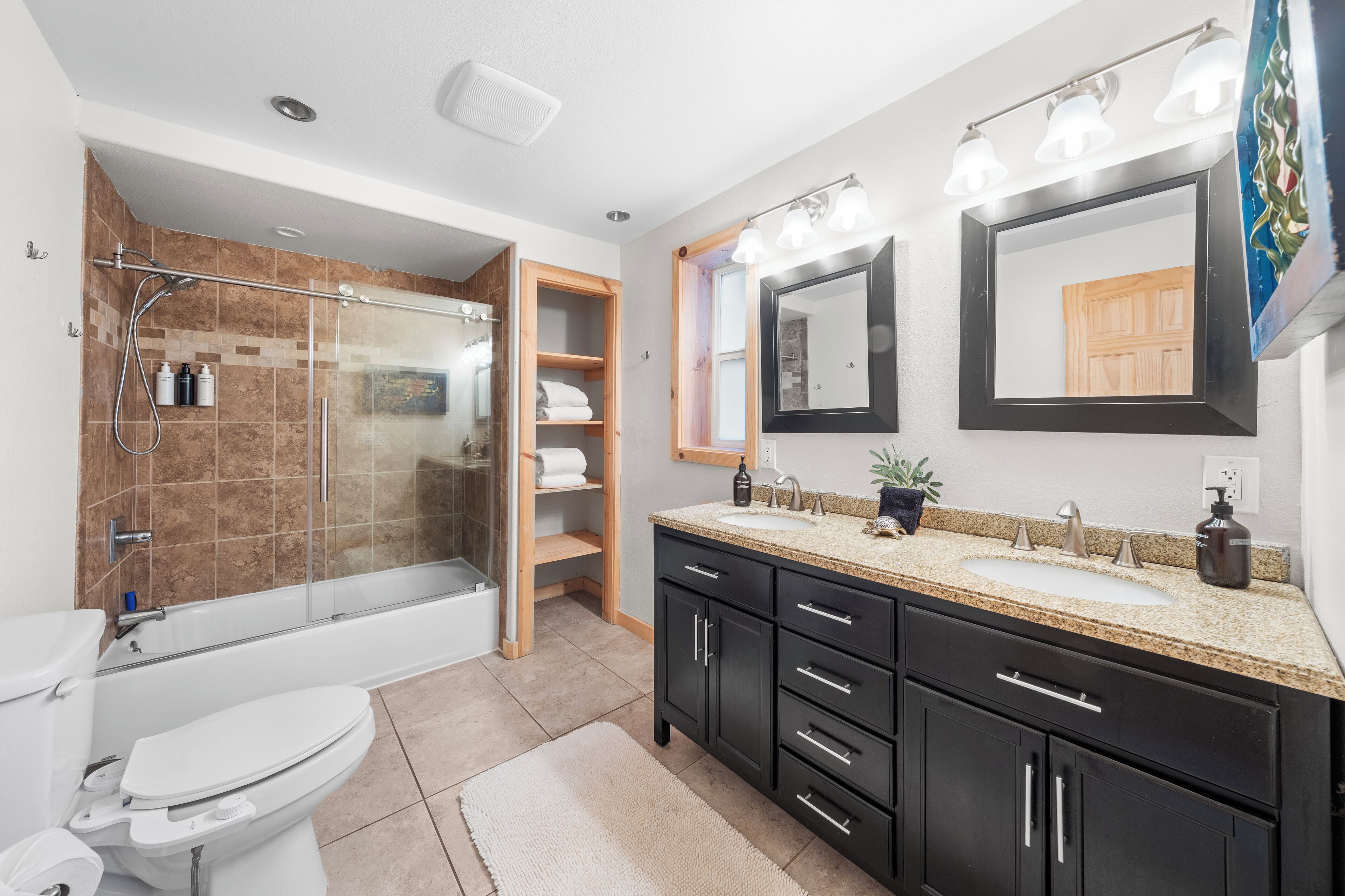 Une salle de bain moderne avec une douche à parois de verre, des toilettes, un lavabo avec un meuble-vasque et un grand miroir.