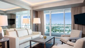 A modern hotel room with a sofa, armchair, coffee table, and a large window offering a city view. - 2 Connecting Suites at a 5 ⭐️ Hotel (Fort Lauderdale)