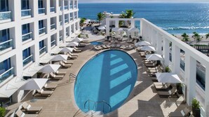 A hotel with a pool, lounge chairs, and a view of the ocean. - 2 Connecting Suites at a 5⭐️ Hotel (Fort Lauderdale)