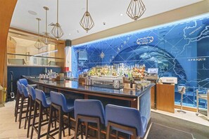 A bar area with a long counter, multiple bar stools, and a wall with a map.