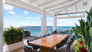 An outdoor patio with a wooden table and chairs, surrounded by plants, overlooking a beach and ocean. - 2 Connecting Suites at a 5⭐️ Hotel (Fort Lauderdale)