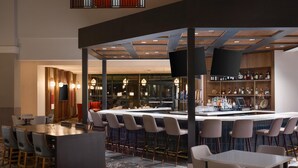 A bar area with a counter, stools, and a seating area with tables and chairs. - 2 Connecting Suites at a  Hotel (Lincoln)