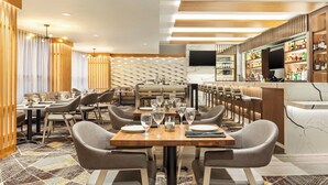 A modern restaurant with a bar area, wooden paneling, and a patterned carpet. - 2 Connecting Suites at a 4⭐️ Hotel (Seattle)