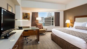 A hotel room with a bed, a desk, a television, a chair, and a view of the cityscape. - 2 Connecting Suites at a 4⭐️ Hotel (Seattle)