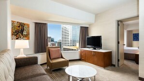 A hotel room with a sofa, armchair, TV, and a dining table. - 2 Connecting Suites at a 4⭐️ Hotel (Seattle)