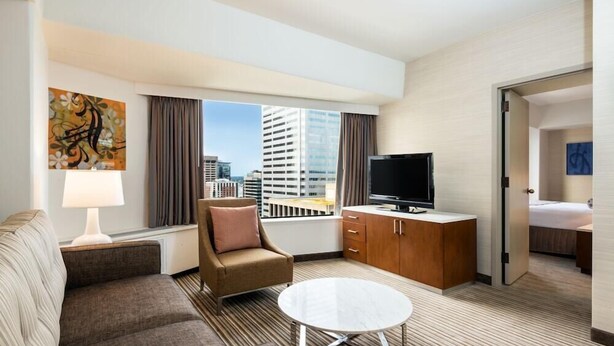 A hotel room with a sofa, armchair, TV, and a dining table. - 2 Connecting Suites at a 4⭐️ Hotel (Seattle)