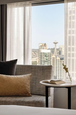 A hotel room with a view of a city skyline, a sofa, a small table with a book and a vase with flowers. - 2 Connecting Suites at a 4⭐️ Hotel (Seattle)