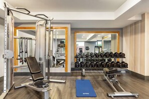 A gym with weightlifting equipment, dumbbells, and exercise mats.