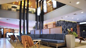 A modern lobby with a sectional sofa, wooden chairs, a reception desk, and a large potted plant. - 2 Connecting Suites at a 4⭐️ Hotel (Seattle)