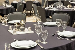 A dining area with round tables set for service, each with plates, cutlery, and glasses.