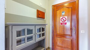 A hallway with a wooden door marked "PROHIBIDO FUMAR" (No Smoking) and a gray cabinet with glass doors. - Spectacular apartment with sunset ocean views in Fanabe Beach with free WIFI (Costa Adeje)