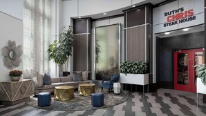 A modern lobby with a reception desk, seating area, and a large window with a view. - 2 Connecting Suites at a  Hotel (Kennesaw)