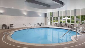 An indoor swimming pool with a tiled floor, metal pool ladders, and chairs around the perimeter. - 2 Connecting Suites at a  Hotel (Kennesaw)