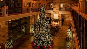 Een ruime lobby met een grote kerstboom, stenen muren en een houten trap.