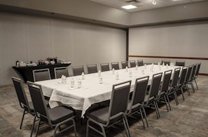 A conference room with a long table, chairs, and a buffet area with food and drinks.