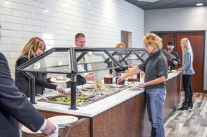 A buffet setup with multiple food stations and a counter where guests are serving themselves. - 2 Connecting Suites at a  Hotel (Fargo)