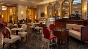 A hotel lobby with seating areas, a bar, and a display case. - 2 Connecting Suites at a 5⭐️ Hotel (New Orleans)