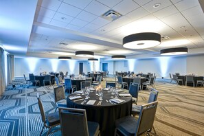 Un salón de conferencias con mesas redondas, sillas e iluminación colgante.